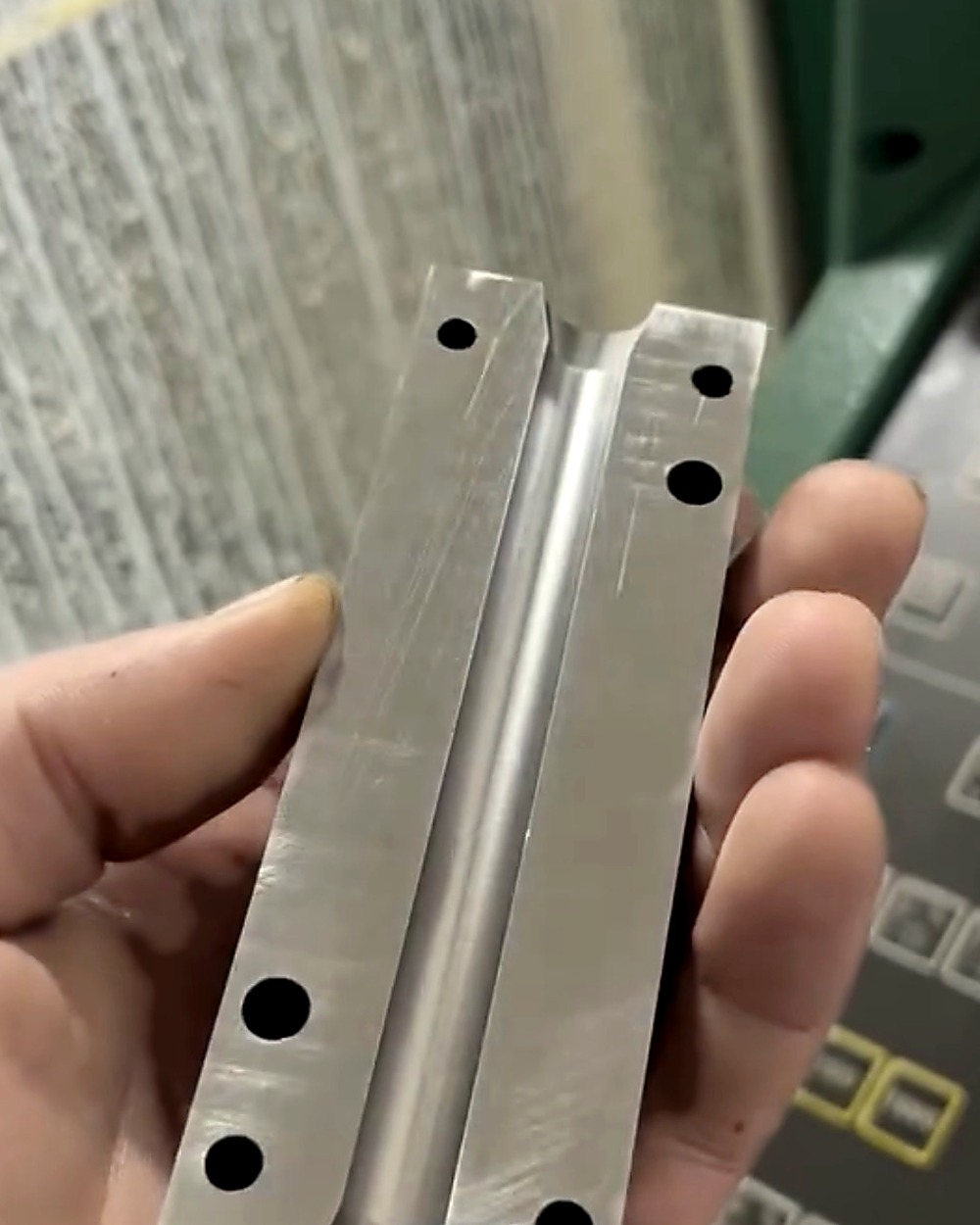 Aluminijumski deo sa uzdužnim žlebom, ispred upravljačke table mašine